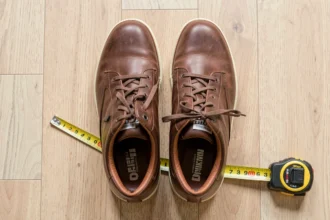 Paire de baskets posée à côté d'un mètre ruban sur un parquet clair
